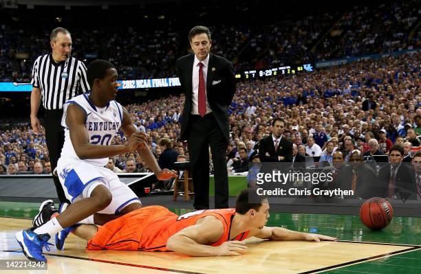Kyle Kuric of the Louisville Cardinals goes after a loose ball in front of Doron Lamb of the Kentucky Wildcats as head coach Rick Pitino of the...