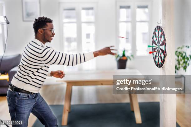 a cheerful african is having a party and enjoying a dart game. - throwing darts stock pictures, royalty-free photos & images