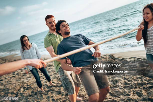 amigos multiculturales divirtiéndose junto con el juego de limbo en la playa - limbo fotografías e imágenes de stock