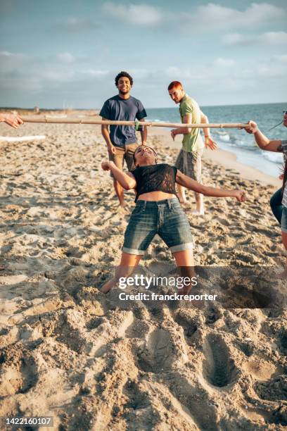 amigos multiculturales divirtiéndose junto con el juego de limbo en la playa - limbo fotografías e imágenes de stock