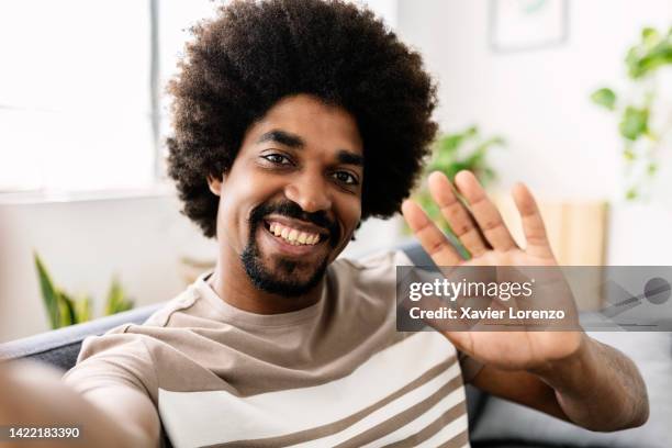 pov or point of view of cheerful young afro american man waving hand while having an online virtual video call using mobile phone chat application at home - zoom date stock pictures, royalty-free photos & images