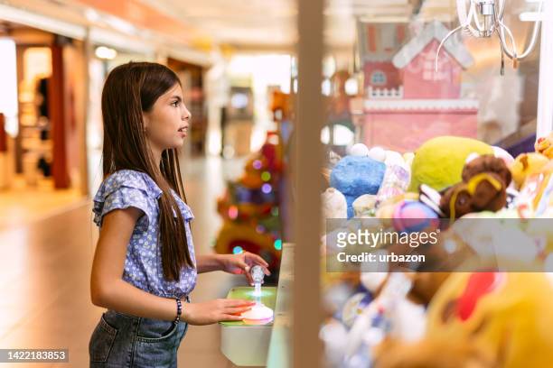 young girl playing a claw crane game - claw machine stock pictures, royalty-free photos & images