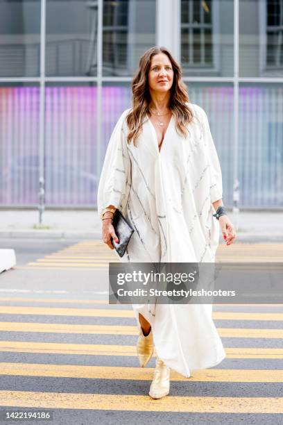 Dana Schweiger, wearing a white caftan dress with silver stripes, designed by herself, during a streetstyle shooting at Berlin Fashion Week on...