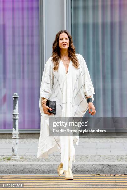 Dana Schweiger, wearing a white caftan dress with silver stripes, designed by herself, during a streetstyle shooting at Berlin Fashion Week on...