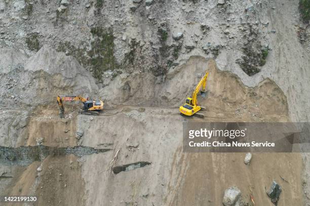 Workers use excavators to clear a landslide along a road that connects Moxi town and Hailuogou National Glacier Forest Park on September 9, 2022 in...