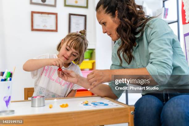 disabled pupil and her teacher doing math - down syndrome girl stock pictures, royalty-free photos & images