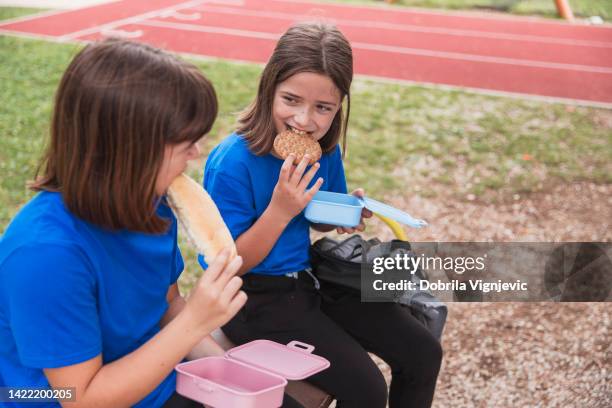 scolari che pranzano e tengono le scatole per il pranzo - girls laughing eating sandwich foto e immagini stock