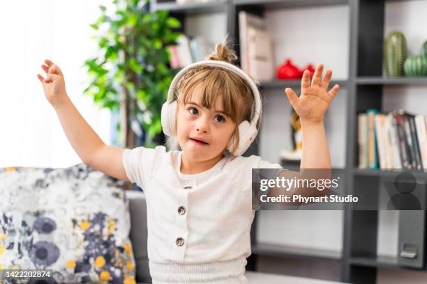 menina síndrome de down em casa usando fones de ouvido e dançando - autism - fotografias e filmes do acervo