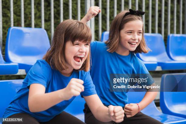excited girls sitting at stadium and supporting their sports team - kid cheering stock pictures, royalty-free photos & images