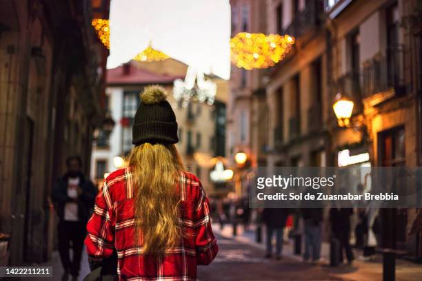 teenage girl with knitted hat walking down the street at christmas - roupa quente imagens e fotografias de stock