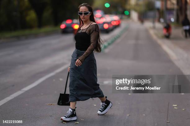 Josi Liza is seen wearing silver shades, long necklace, black top and black fishnet longsleeve, black nylon cargo long skirt, black leather shoulder...