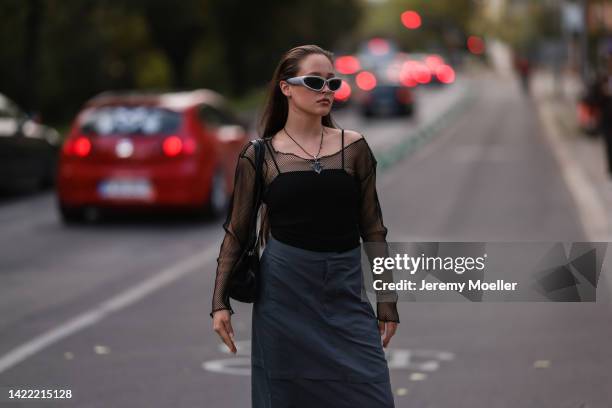 Josi Liza is seen wearing silver shades, long necklace, black top and black fishnet longsleeve, black nylon cargo long skirt, black leather shoulder...