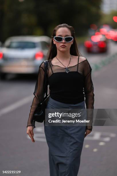 Josi Liza is seen wearing silver shades, long necklace, black top and black fishnet longsleeve, black nylon cargo long skirt, black leather shoulder...