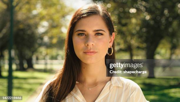 face, beauty and park with a woman outside in summer and looking confident against a sunny and natural background. closeup head portrait of a young female enjoying a day in a garden with sunlight - earrings stockfoto's en -beelden