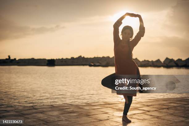 beautiful indian girl traditional dancing on the beach - buikdanseres stockfoto's en -beelden