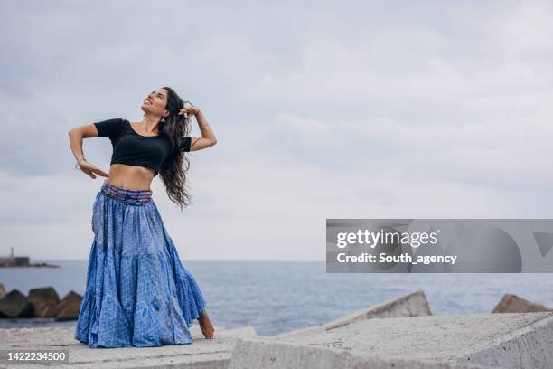 beautiful indian girl traditional dancing on the beach - belly dancer stock pictures, royalty-free photos & images