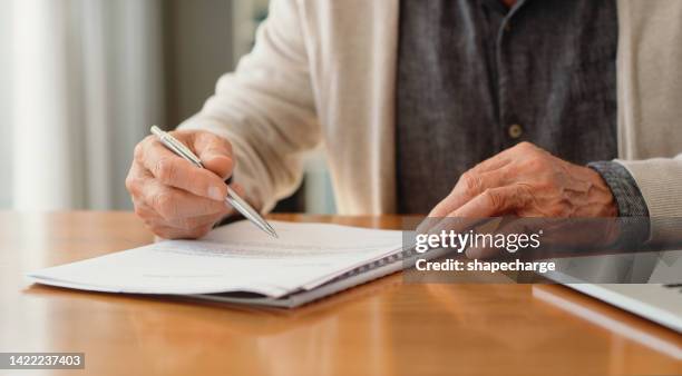 les mains d’un homme de pension lisent des documents de retraite sur la police, les options de placement et la couverture funéraire tout en planifiant les finances, les assurances et le budget à la maison. signature du testament, du document juridique - testament photos et images de collection