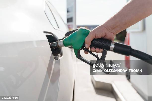 man's hand holding green petrol pump and feeling car - benzinestation stockfoto's en -beelden