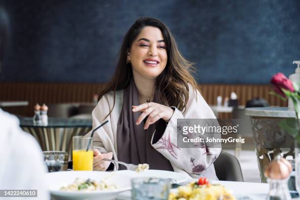 cheerful saudi woman dining at restaurant with friends - saudi lunch stock pictures, royalty-free photos & images