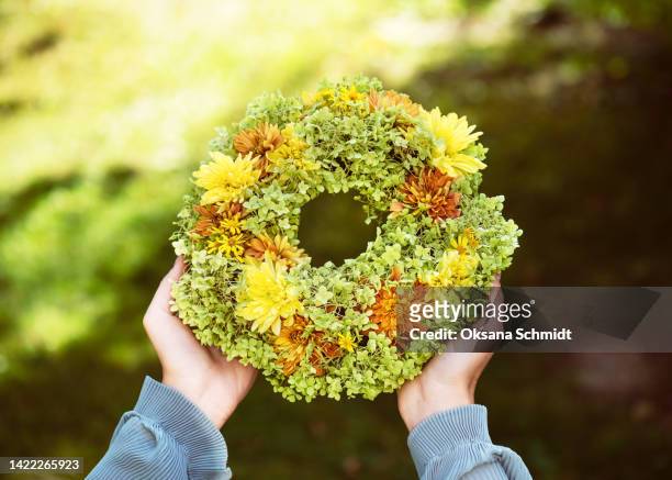 beautiful handmade wreath of colorful autumn flowers in girl's hands in the garden. - heritage round one stock-fotos und bilder