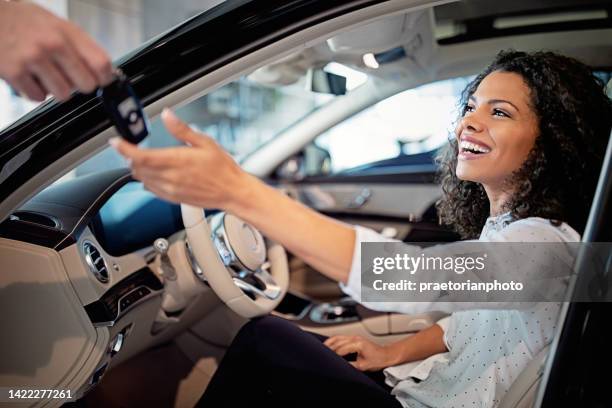 car dealer is giving key for a new car to a woman - chave de carro imagens e fotografias de stock