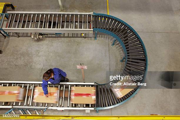 worker scanning boxes on a conveyor belt - conveyer belt stockfoto's en -beelden