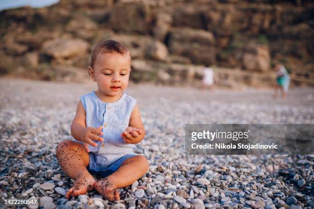 baby is playing on the beach with pebbles - pensive bildbanksfoton och bilder
