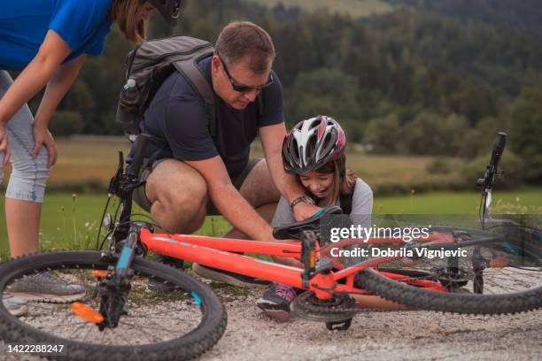 man helping screaming girl after cycling injury - familie fietsen close up stockfoto's en -beelden