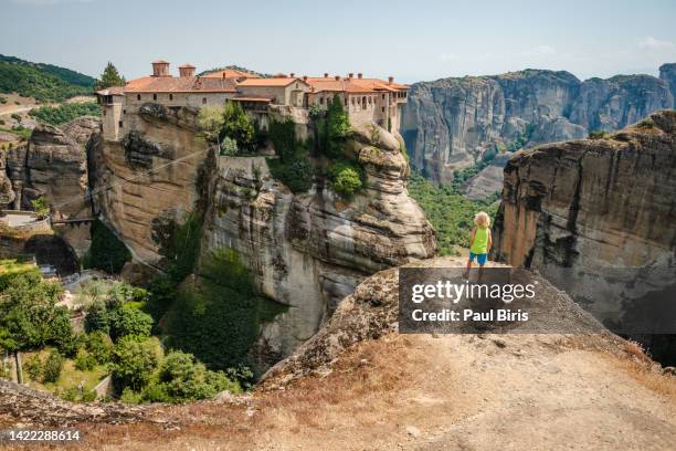 blonde child looking at monastery of the holy trinity, meteora monasteries, trikala, thessaly, greece. - meteora greece stock pictures, royalty-free photos & images