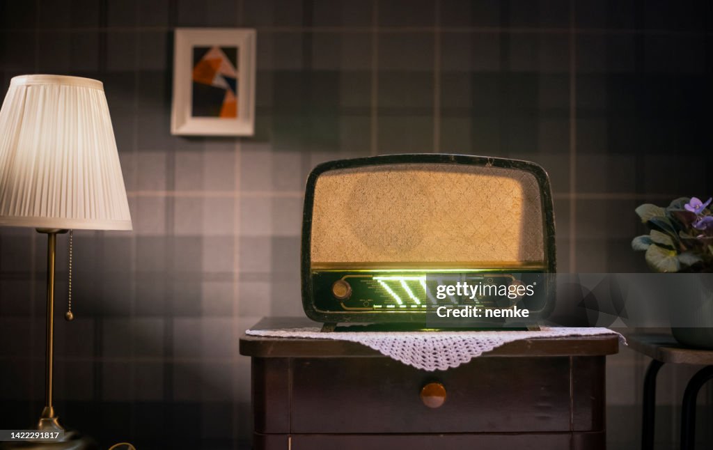 Old retro radio on table against vintage wall background
