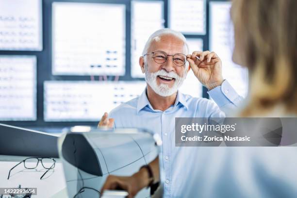 älterer mann, der augen auf der suche nach einer guten brille untersucht - eye doctor stock-fotos und bilder