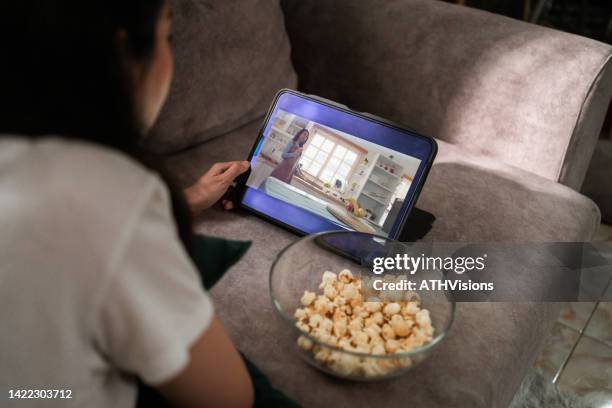sopra lo schermo del dispositivo a spalla di donna che guarda film commedia in streaming su tablet digitale a casa. - video on demand foto e immagini stock