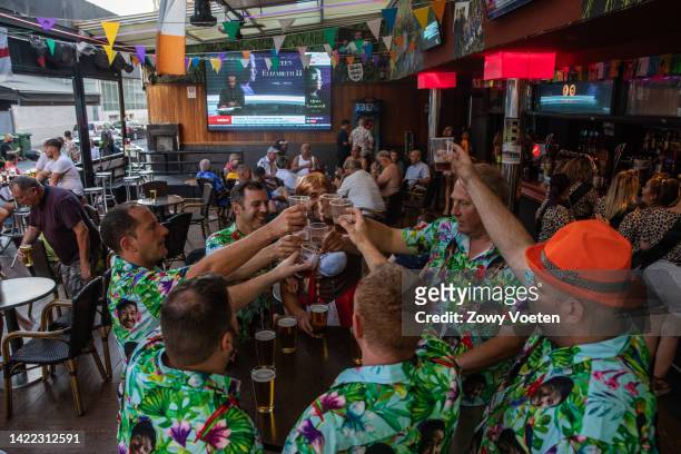 Group of tourists celebrate a bachelor party toasting with beer and shouting the famous slogan, God Save the Queen, while in the background on a...