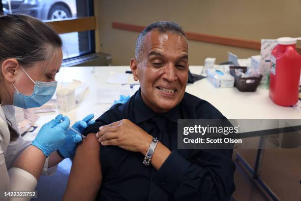 Felipe Sanchez gets a COVID-19 booster shot from pharmacist Patricia Pernal during an event hosted by the Chicago Department of Public Health at the...