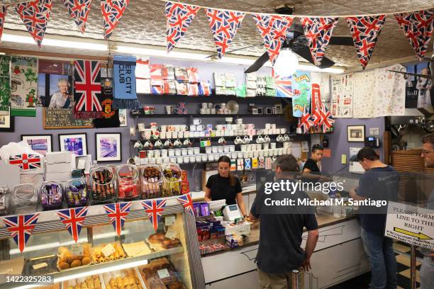 Photo of Queen Elizabeth II is seen as customers make purchases at Myers of Keswick on September 09, 2022 in New York, New York. Queen Elizabeth, the...