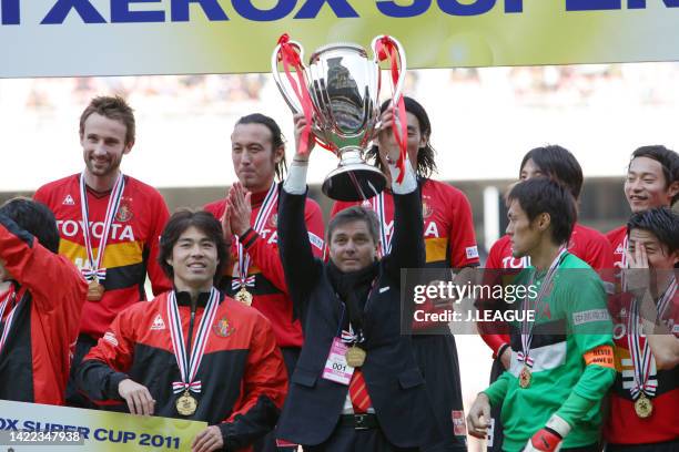 Head coach Dragan Stojkovic of Nagoya Grampus lifts the trophy at the award ceremony following the Fuji Xerox Super Cup between Nagoya Grampus and...