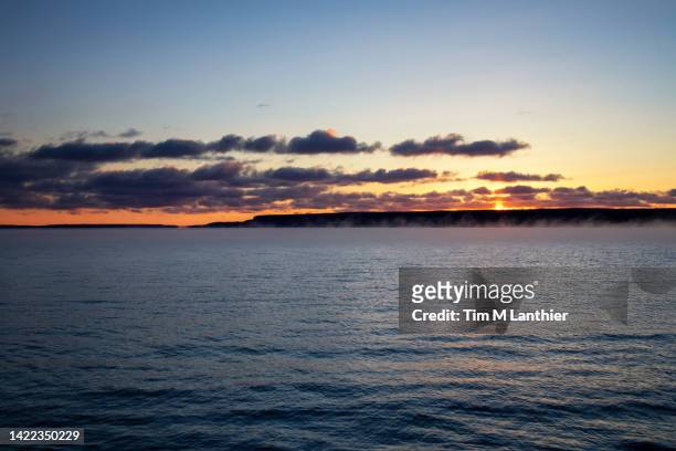 sunrise over lake with cliffs silhouetted in the background - lake huron stock pictures, royalty-free photos & images