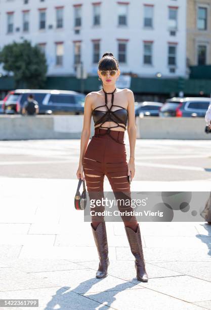 Katya Tolstova is seen wearing high waisted rust brown ripped pants, top, cowboy mid high boots Wandler, Gucci bag, Alain Mikli sunglasses outside...