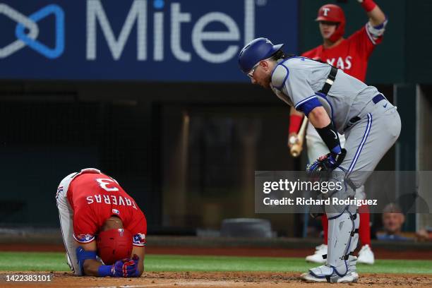 Leody Taveras of the Texas Rangers kneels on the ground after being hit by a pitch as Danny Jansen of the Toronto Blue Jays looks onin the seventh...