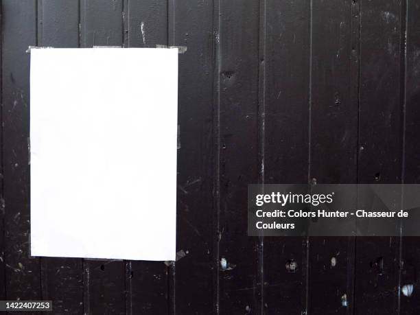 an empty white poster on a black painted wooden plank wall in paris, france - poster wall stock-fotos und bilder