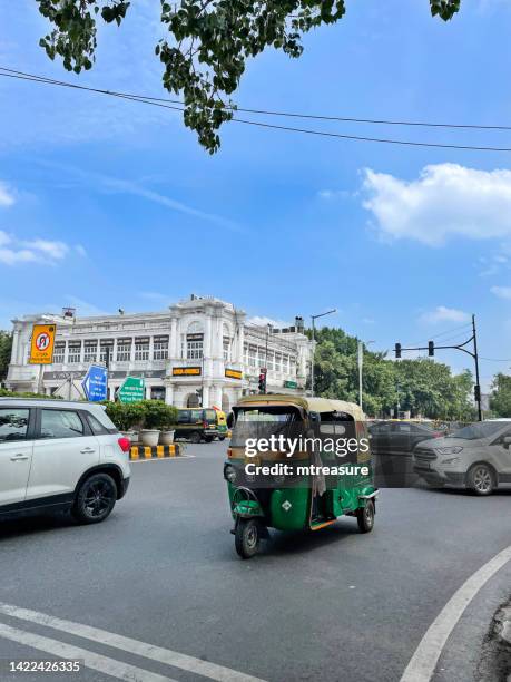 image of indian auto rickshaw taxi cab, cars and yellow and green tuk tuk transporting passengers around connaught place, new delhi, india - connaught place bildbanksfoton och bilder