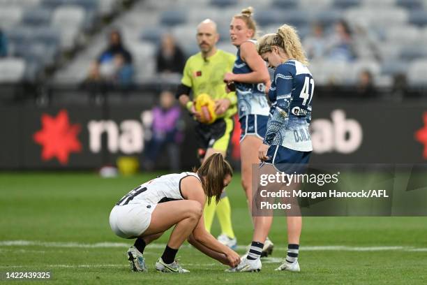 Chloe Molloy of the Magpies ties the shoe laces of Georgie Prespakis of the Cats during the round three AFLW match between the Geelong Cats and the...