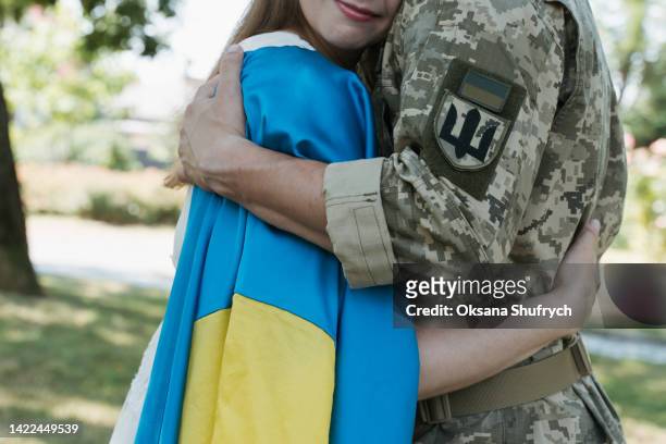 ukrainian army soldier hugs woman with ukrainian flag - ucrânia - fotografias e filmes do acervo
