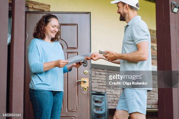 mail delivery confirmation and sign contracts. delivery man get contract form to female customer - send parcel stock pictures, royalty-free photos & images