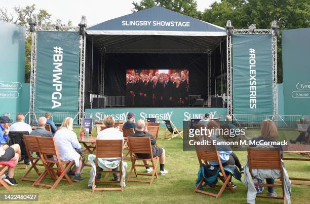Spectators gather around LED Screens in the Fans Village to watch the proclamation of King Charles III during Round Two on Day Three of the BMW PGA...