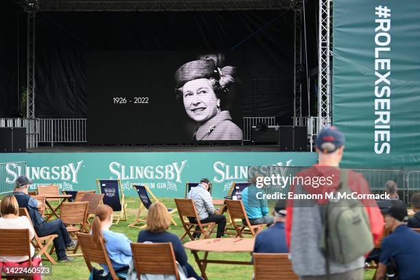 General view as the LED Screen in the Fans Village displays an image of Her Majesty, Queen Elizabeth II, as competitors and spectators pause for a...