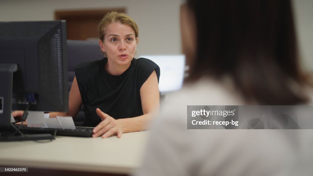 Female hospital receptionist talking with patient in hospital