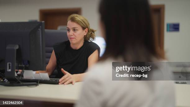 female hospital receptionist talking with patient in hospital - sekreterare bildbanksfoton och bilder