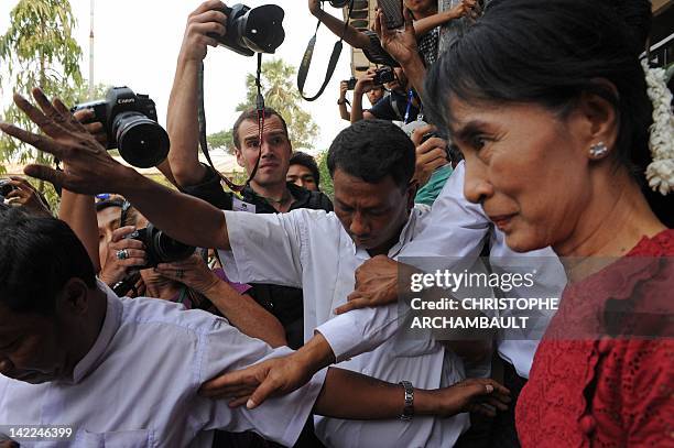 Myanmar opposition leader Aung San Suu Kyi is surrounded by journalists as she leaves after visiting a polling station in the constituency where she...