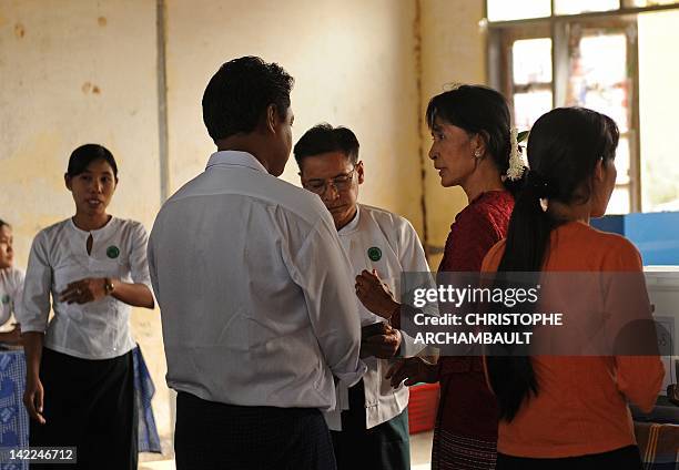 Myanmar opposition leader Aung San Suu Kyi talks with Election Commission officials as she visits a polling station in the constituency where she...